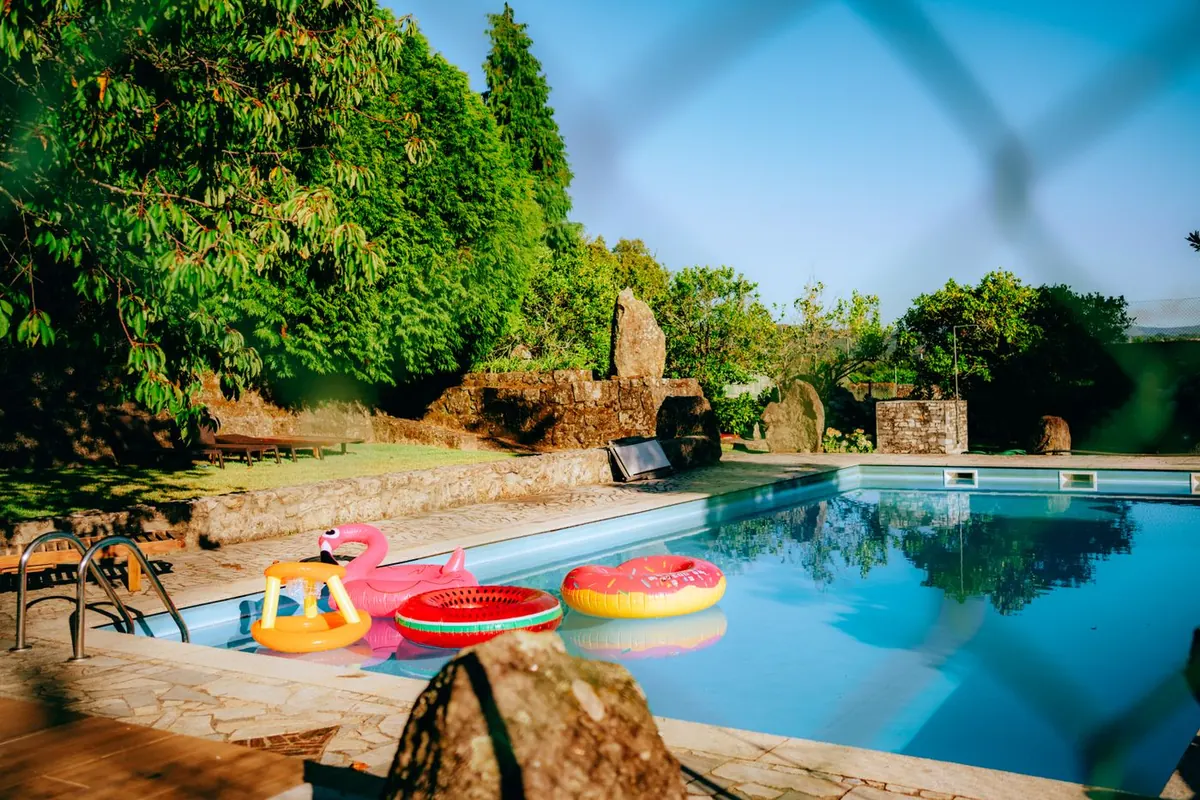 Backyard pool with floats, seen through a chain link fence